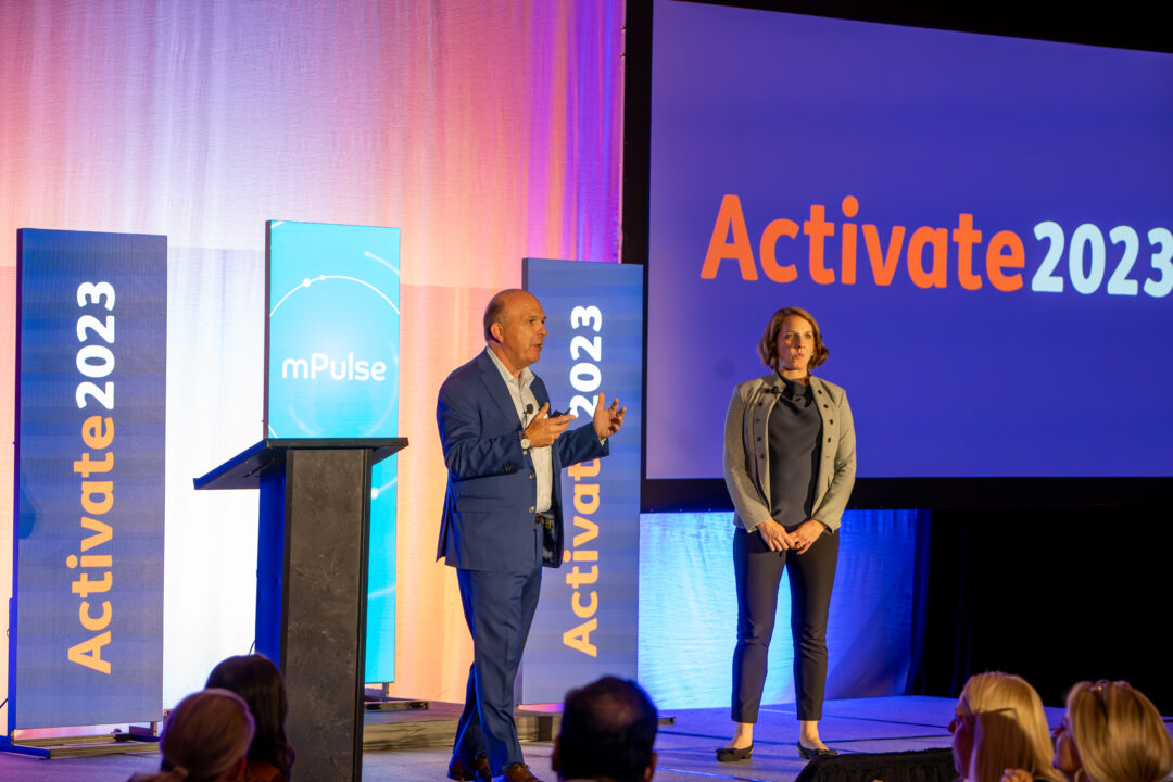 Speakers presenting on stage at the Activate 2023 conference with branding and a large screen.
