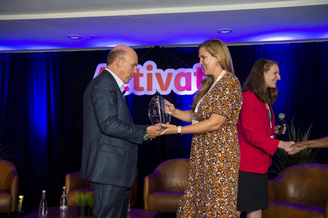 Man presenting an award to a woman on stage at an event.