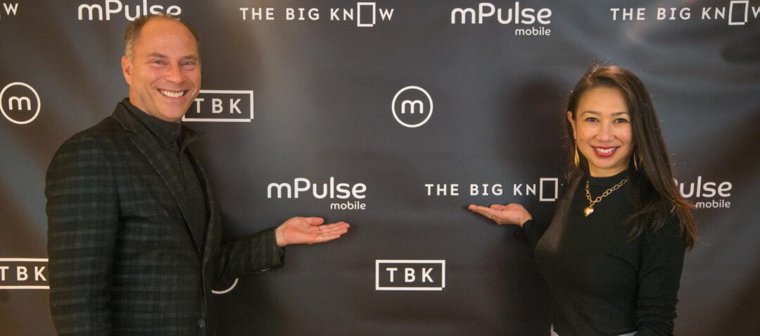 Chris and Allison posing in front of the mPulse and The Big Know branded backdrop.