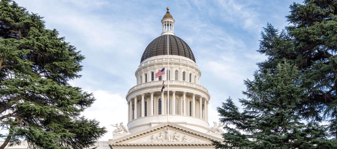 California State Capitol building dome framed by trees.