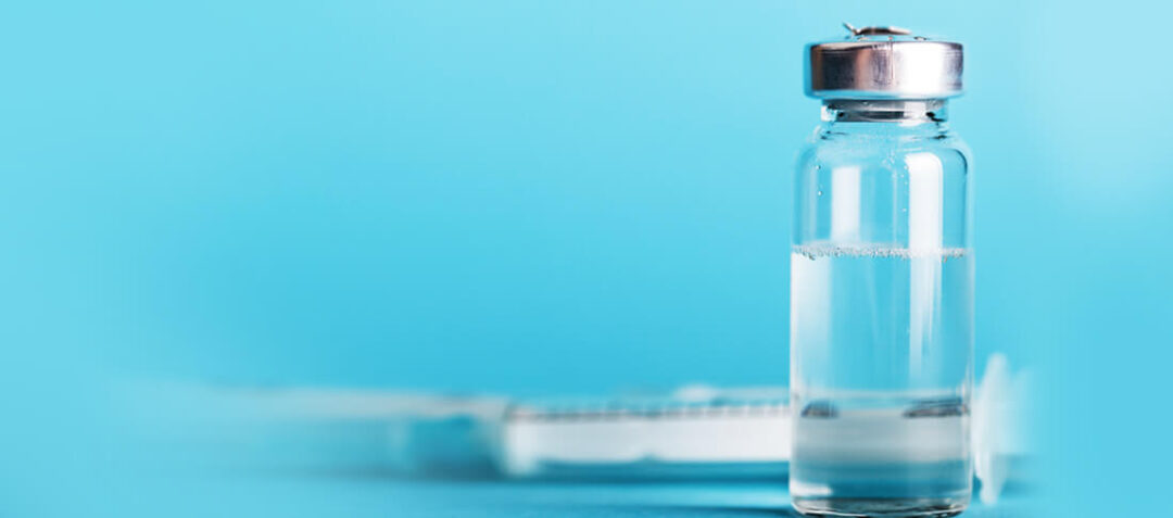 Clear glass vaccine vial filled with liquid against a blue background